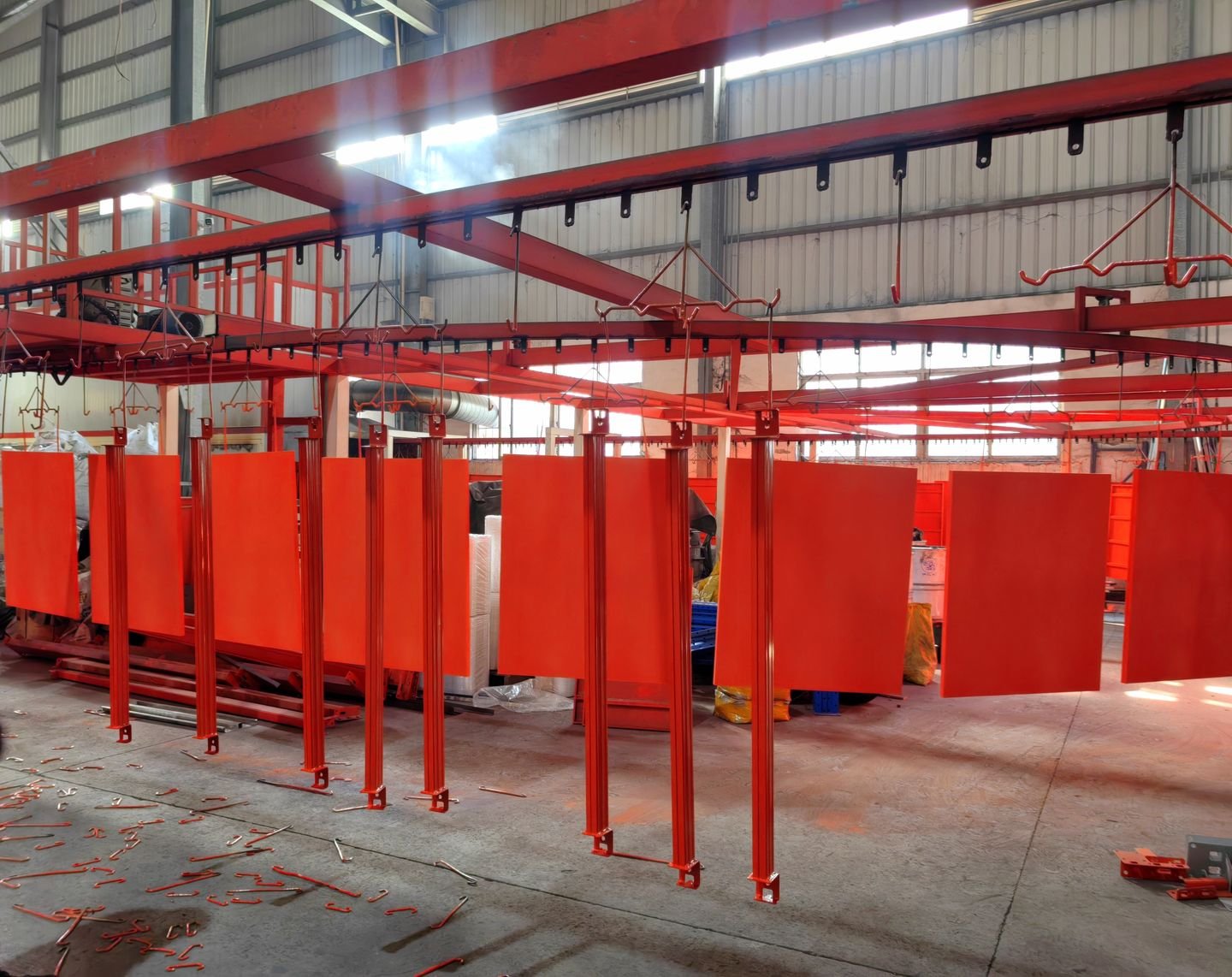 Red powder-coated uprights hanging from an overhead conveyor